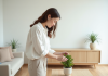 Style minimaliste : les avantages pour votre décoration intérieure ! Jeune femme arrangeant une plante verte dans un vase en céramique dans un intérieur lumineux
